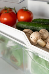 Fresh mushrooms, tomatoes and cucumbers in the refrigerator. Healthy diet nutrition. Vegetarian Vegetable. Close-up