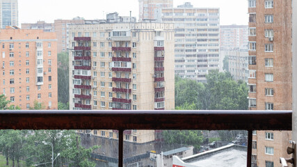 panoramic view of wet balcony railing and residential district in rain in Moscow city in summer