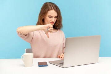 Dislike! Upset displeased woman employee showing thumbs down when talking on video call, expressing disapproval, having online conference at home office. indoor studio shot isolated on blue background