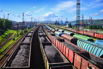 Fototapeta premium Freight station with long cargo trains, wagons loaded with coal at the background of blue sky with clouds. Awesome city scenery in Murmansk, Kola peninsula, Nortern Russia.