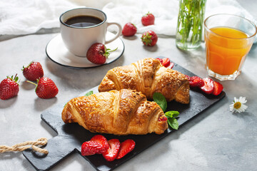 Tasty breakfast. Fresh croissants and strawberries, black coffee and orange juice