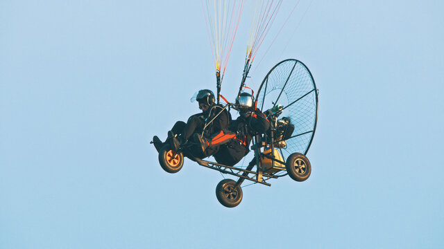 Tandem Paramotor Gliding - two men flying and gliding in the air. High quality photo