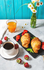 Tasty breakfast. Fresh croissants and strawberries, black coffee and orange juice.