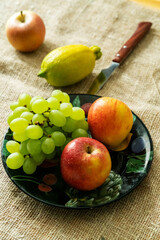 lemon, apples and green grapes on a wooden table.