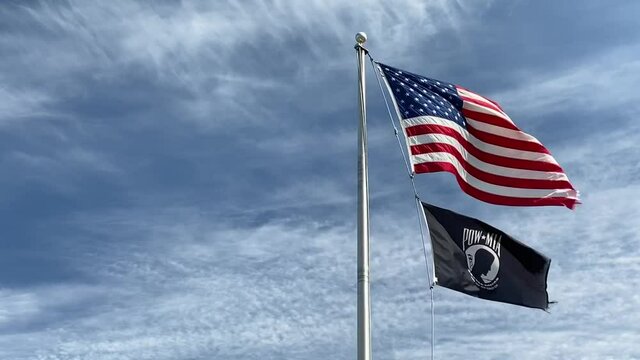 American and veterans flags on a flagpole in slow motion.