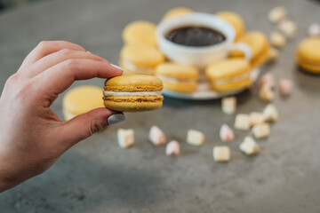 Handful of Delicious Yellow French Macarons on the Table with Cup of Coffee and Marshmallow