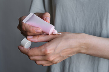 Tube with cream in the hands of a girl. Skin care. Medical and dermatological cosmetics for hands. Beauty and health of a woman. Spa body treatments. Container with natural cream close-up. Blank space