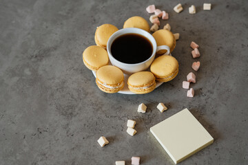 Obraz na płótnie Canvas Handful of Delicious Yellow French Macarons on the Table with Cup of Coffee and Marshmallow