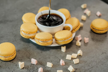 Handful of Delicious Yellow French Macarons on the Table with Cup of Coffee and Marshmallow