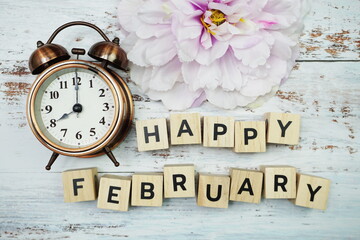 Happy February with alarm clock on wooden background
