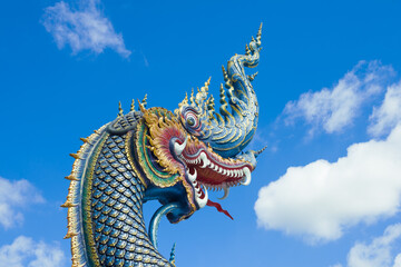 Head of a Thai dragon on a background of blue sky. Detail of the design of the Buddhist temple Wat...