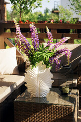A bouquet of bright purple lupins stands on the table for interior decoration purposes