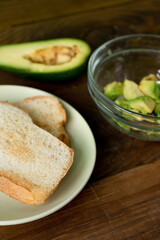 Fried bread for toasts and avocado for breakfast in the morning on brown woodwn table. Close-up