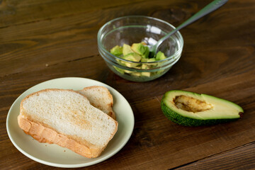 Fried bread for toasts, avocado and honey for breakfast in the morning on brown woodwn table on green background. 