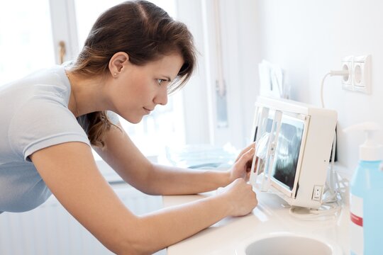 Female dentist looking at dental panoramic x-ray image. Side view.