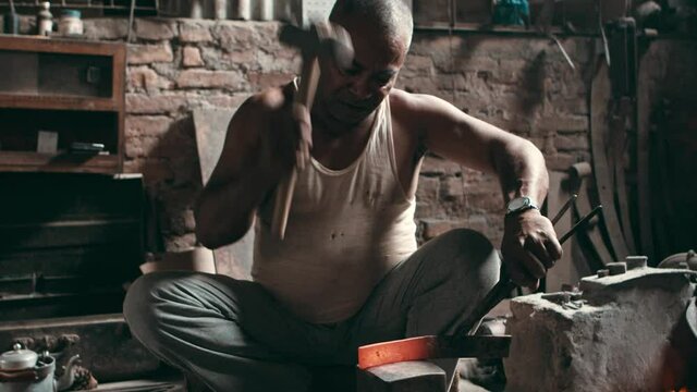 Rural blacksmith hammering a metal piece on an anvil
