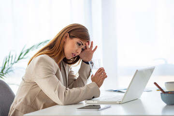 Shot of a young businesswoman looking stressed out while working in an office. When the road to success leads to stress. Woman suffering from stress while using a computer at her work desk