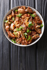 fried chicken offal liver, heart and stomachs with onions, tomatoes and spices close-up in a bowl. vertical top view