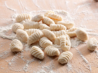 Gnocchi sobre tabla de madera con harina, vista cenital. Gnocchi on wooden board with flour, overhead view.