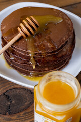 Chocolate pancakes with honey for breakfast on wooden table. Vertical