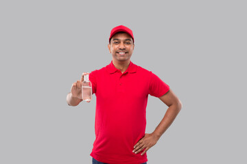 Naklejka premium Indian Delivery Man Holding Hands Sanitizer. Hands Antiseptic. Man in Red T shirt. Health, Isolation Concept