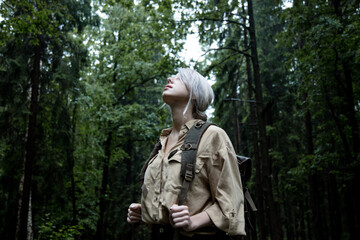 Fototapeta na wymiar Blonde woman with backpack in rainy day in forest