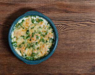 baked cutlets in spinach sauce with cheese on a wooden table in a baking dish