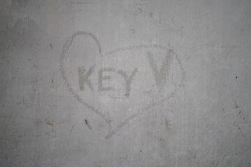 Key wording in scratching heart sign on old cement wall.