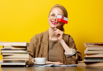 blonde woman with flag of Poland and books on yellow background