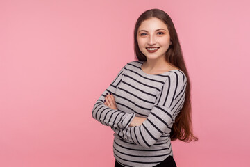 Portrait of joyful self-assured woman in striped sweatshirt looking at camera with toothy smile,...