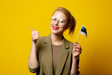 Style blonde woman in jacket with Estonian flag on yellow background