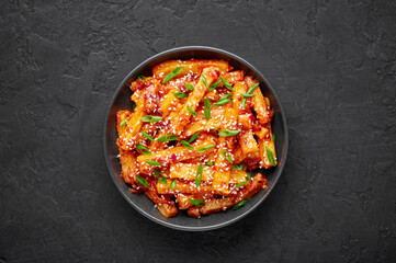Honey Chilli Potato or Schezwan Aloo in black bowl on dark slate table top. Chilli Potatoes is indo-chinese cuisine dish. Authentic asian food. Indian meal. Top view