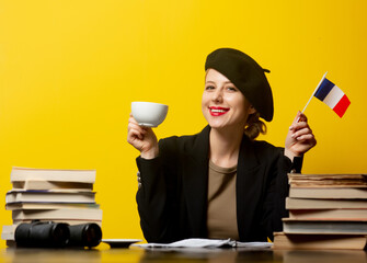 Style blonde woman in beret with French flag and books around on yellow background