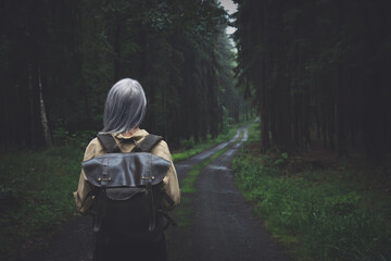 Blonde woman with backpack in rainy day in forest