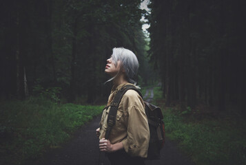 Blonde woman with backpack in rainy day in forest