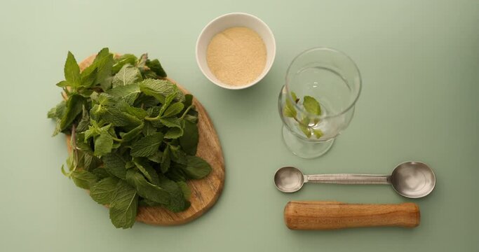 Putting mint leaves and sugar in glass and then mashing them with muddler to make mint mojito coffee