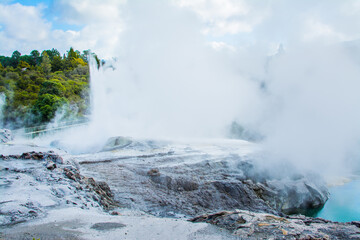 Steam rises as a geyser erupts over rocky field