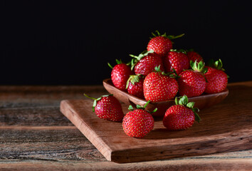 Strawberry in a plate on a wooden background.