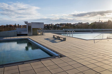 Two outdoor swimming pools filled with crystal clear water during beautiful sunset, blue sky background
