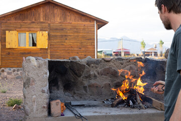 Jeune homme devant un barbecue et une cabane en bois