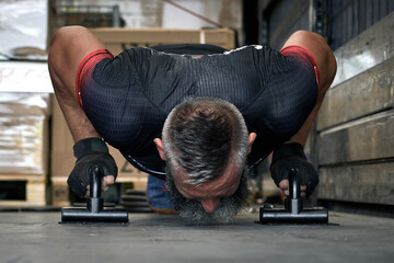 Man doing push-ups training aerobic fitness inside a warehouse making a great effort.