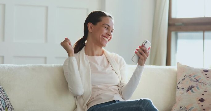 Overjoyed young mixed race girl looking at cellphone screen, celebrating online lottery win notification. Happy millennial woman buyer shopper excited by great news, sms with promotions sale code.