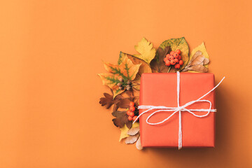 Holiday present. Celebration. Gift box. Autumn floral decor Orange background