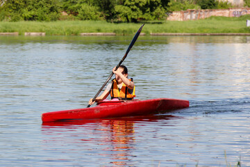 athlete on a red kayak rowing on the river