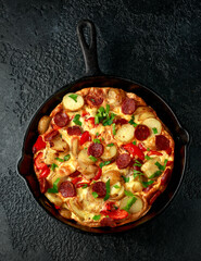 Frittata made of eggs, potato, chorizo, red bell pepper and greens in iron cast pan