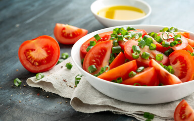 Tomato salad with spring onion and herbs in white bowl. Healthy summer food