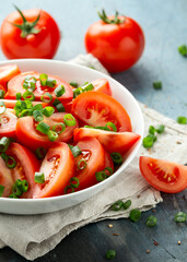 Tomato salad with spring onion and herbs in white bowl. Healthy summer food