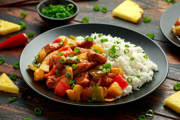 Pineapple and Chicken in sweet and sour sauce with bell pepper, rice and spring onion in black plate