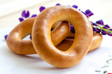 Bagels on a napkin with embroidery and purple flowers. Pleasant light composition.