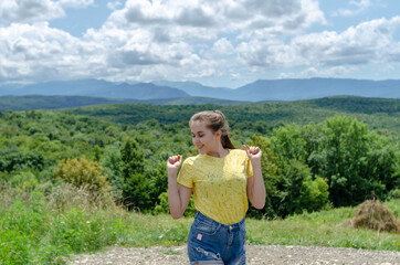 Young beautiful girl under the sun on the background of mountains and forests in summer, summer vacation in the mountains.